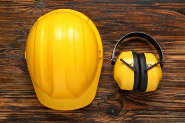 Ahşap arka planda sert şapka ve koruyucu kulaklık.