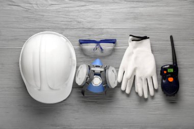 Gri ahşap arka planda sert şapka ve güvenlik ekipmanları