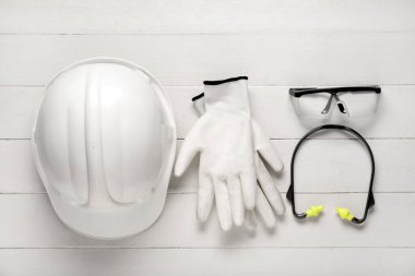 Beyaz ahşap arka planda güvenlik ekipmanı olan sert şapka