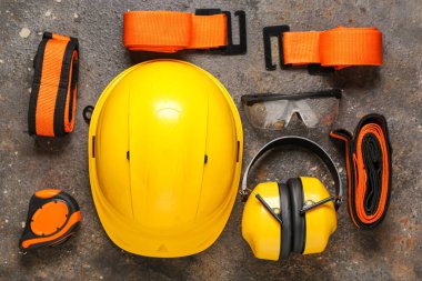 Sert şapka, koruyucu kulaklıklar ve gri grunge arka planda emniyet kemerleri.