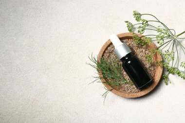 Gri grunge arka planda tohumlu bir şişe dereotu yağı.