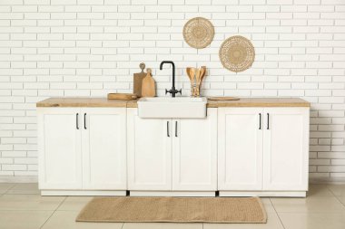 Beyaz tezgahlı, çatallı ve lavabolu şık bir mutfak.