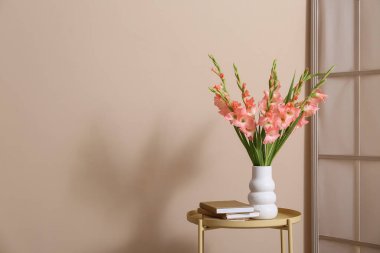 Kitaplar ve vazo içinde güzel gladiolus çiçekleri olan oturma odasındaki masada, yakın plan.