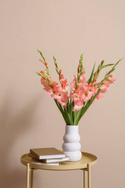 Kitaplar ve vazo içinde güzel gladiolus çiçekleri olan oturma odasındaki masada, yakın plan.