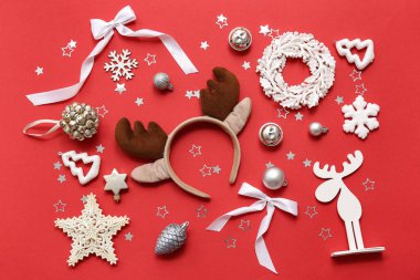 Kırmızı arka planda takılar ve kar taneleri olan geyik boynuzları.