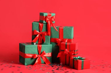Kırmızı arka planda konfeti olan Noel hediyeleri