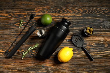 Kahverengi ahşap arka planda modern barmen aletleri ve kokteyl malzemeleri