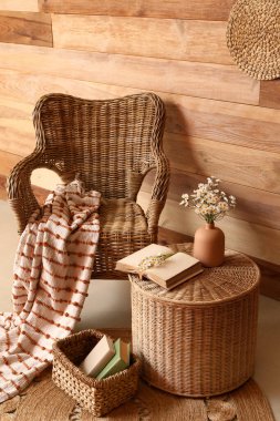 Hasır koltuğu ve kahve masasında suni çiçekleri olan şık bir oturma odası.