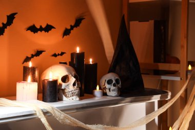 Cadılar Bayramı için dekore edilmiş şöminenin üzerinde yanan mumlar olan kafatasları.