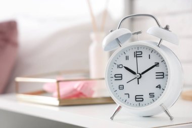 Yatak odasındaki komodinin yanındaki çalar saat, yakın plan.