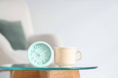 Çalar saat ve fincan çay, oturma odasının içindeki masada, yakın plan.