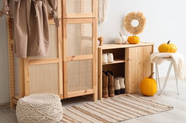 Koridorun içinde dolap, ayakkabı standı ve sonbahar dekoru var.