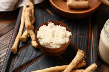 Kesme tahtası, yabanturpu kökleri ve kahverengi ahşap arka planda kâsede sos. Yakın plan.