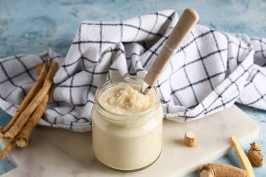 Mermer tepsi, peçete, cam kavanoz ve turp soslu kaşık mavi grunge arkaplan, yakın çekim