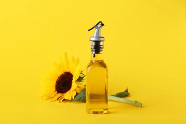 Sarı zemin üzerinde ayçiçeği olan bir şişe yağ.