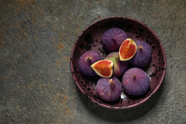 Arka planda taze olgun incirlerle dolu bir kase.