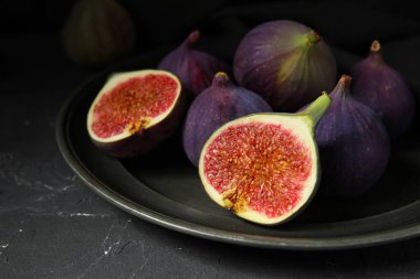 Siyah arka planda taze taze incir tabağı, yakın plan.