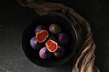 Siyah arka planda taze olgun incirlerle dolu bir kâse