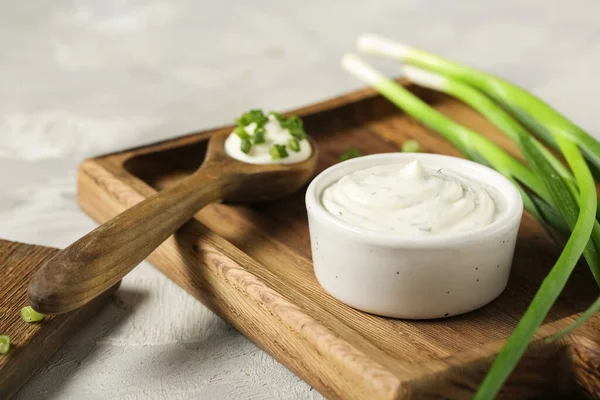 Kase ve bir kaşık lezzetli ekşi krema ve grunge masasında doğranmış yeşil soğan.
