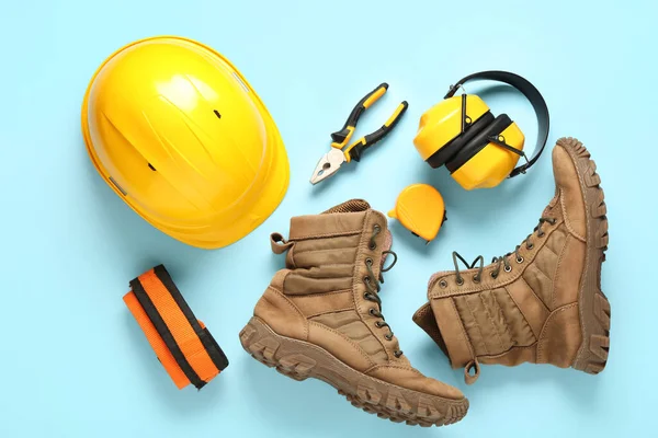 Mavi arka planda sert şapka, botlar ve güvenlik ekipmanları