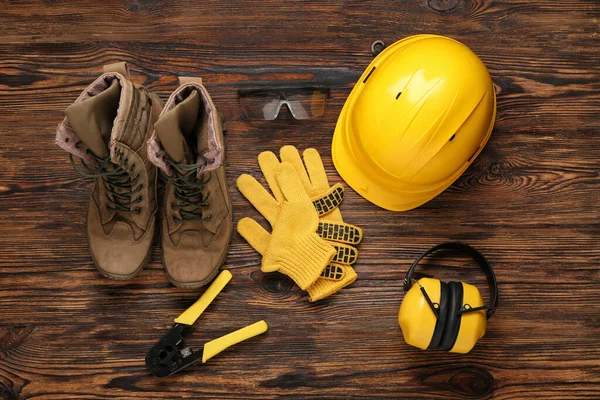 Ahşap arka planda sert şapka, botlar ve güvenlik ekipmanları