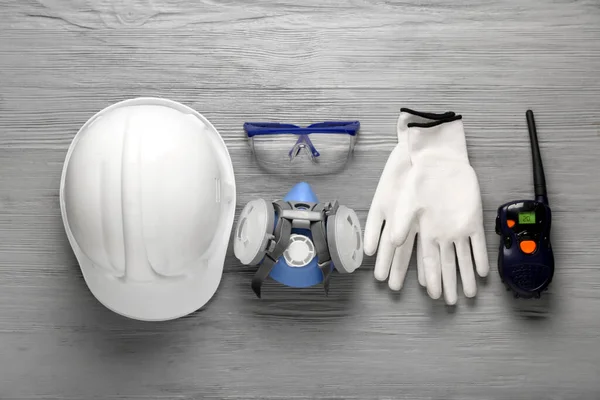 Gri ahşap arka planda sert şapka ve güvenlik ekipmanları