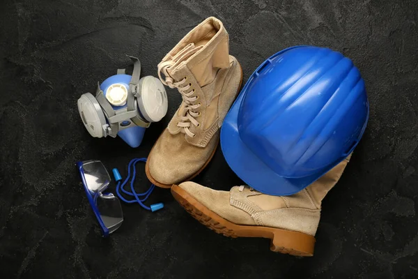 Botlu sert şapka, solunum cihazı ve siyah grunge arka planda güvenlik gözlüğü.