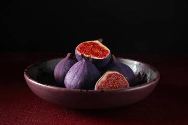 Kırmızı masada taze incir kasesi.