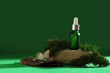 Yeşil zemin üzerinde gerekli yağ, ağaç kabuğu, yosun ve dekoratif taş şişesi bileşimi, yakın plan.