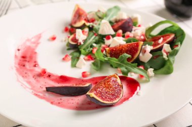 Arka plan olarak beyaz kareli kumaş üzerinde lezzetli incir salatası, yakın plan