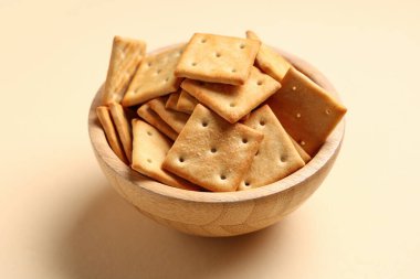 Bej arka planda lezzetli krakerler olan ahşap kase, yakın plan.