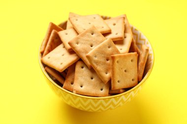 Sarı arka planda lezzetli krakerler olan kase, yakın plan.