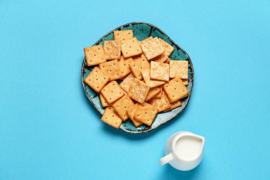Lezzetli kraker tabağı ve mavi arka planda bir sürahi sütle kompozisyon