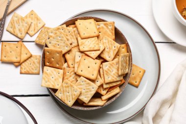 Beyaz ahşap arka planda lezzetli krakerler içeren kompozisyon, yakın plan.