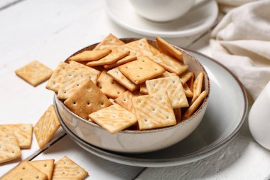 Beyaz ahşap arka planda lezzetli krakerler içeren kompozisyon, yakın plan.