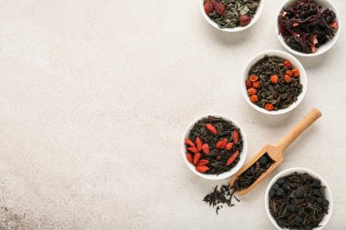 Hafif arkaplanda farklı meyve çayları olan kaseler