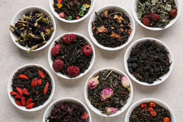 Hafif arkaplanda farklı meyve çayları olan kaseler