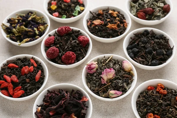 Hafif arkaplanda farklı meyve çayları olan kaseler