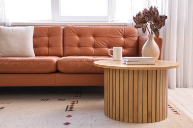 Oturma odasındaki ahşap masada bir fincan sıcak kahve ve kitaplar.