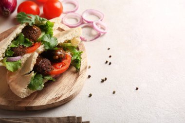 Tahta tabak dolusu nefis pita falafel ve beyaz arka planda taze sebzeler.
