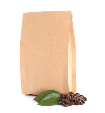 Kahve çekirdekli kağıt torba ve beyaz arka planda yapraklar.