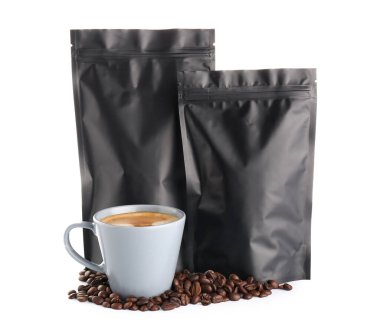 Fasulyeli siyah torbalar ve beyaz arka planda bir fincan sıcak kahve.