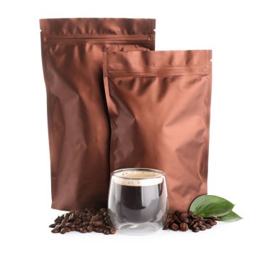 Kahverengi torbalar ve beyaz arka planda bir bardak sıcak kahve.