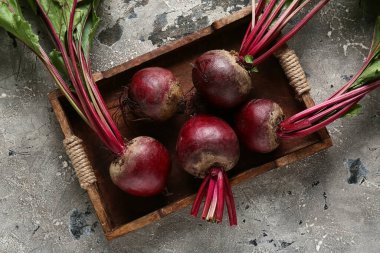 Gri grunge arka planda taze pancar kökleri olan tahta tepsi.