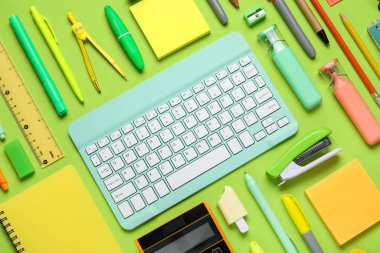 Modern bilgisayar klavyesine sahip kompozisyon ve yeşil arkaplan üzerindeki farklı kırtasiye