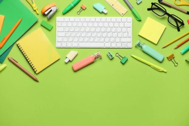Yeşil arkaplanda bilgisayar klavyesi ve farklı kırtasiye malzemesi olan kompozisyon