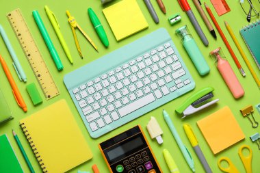 Modern bilgisayar klavyesine sahip kompozisyon ve yeşil arkaplan üzerindeki farklı kırtasiye