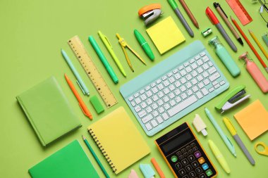 Modern bilgisayar klavyesine sahip kompozisyon ve yeşil arkaplan üzerindeki farklı kırtasiye