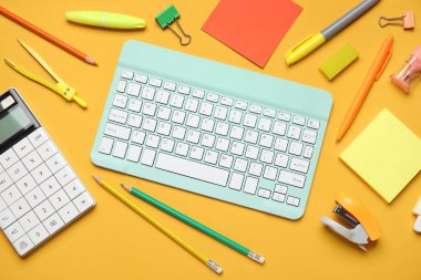 Modern bilgisayar klavyesine sahip kompozisyon ve turuncu arka planda farklı kırtasiye