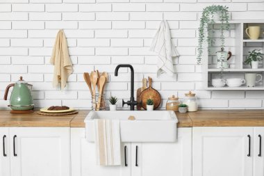 Beyaz tezgahlı, çatallı ve lavabolu şık bir mutfak.